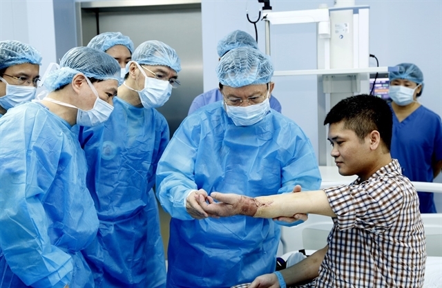 Доктор Май Хонг Банг, директор 108-го Центрального военного госпиталя, проверяет моторику пациента после операции / © Vietnam.net