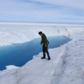 Ученый у протока талой воды в Гренландии