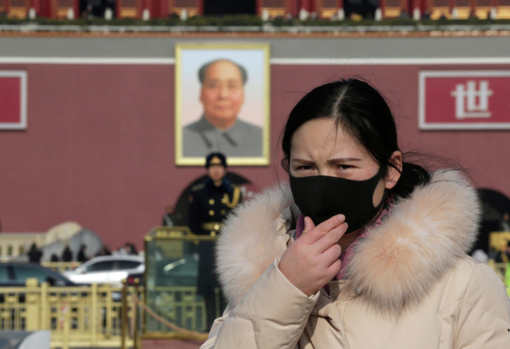 Девушка в маске на площади Тяньаньмэнь в Пекине / © Reuters
