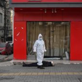 Сотрудники скорой помощи в защитных костюмах проверяют тело мужчины, который упал в обморок на улице и умер. Ухань, 30 января/ © AFP