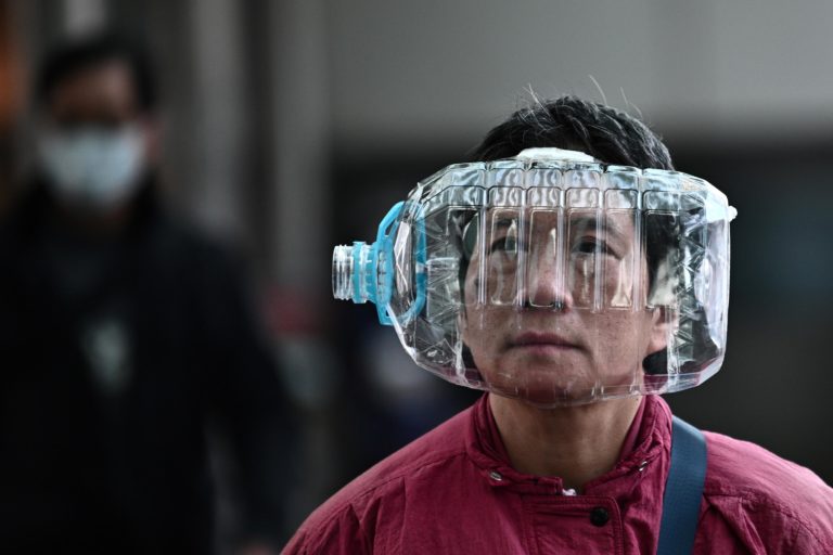 Прохожий с пластиковой бутылкой на лице на улице Гонконга / © AFP