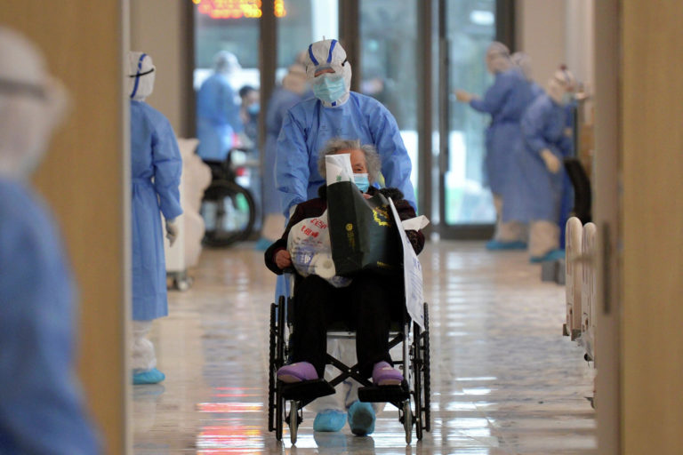 Медработник в защитном костюме везет больного коронавирусом пациента, город Ухань / © Reuters, China Daily