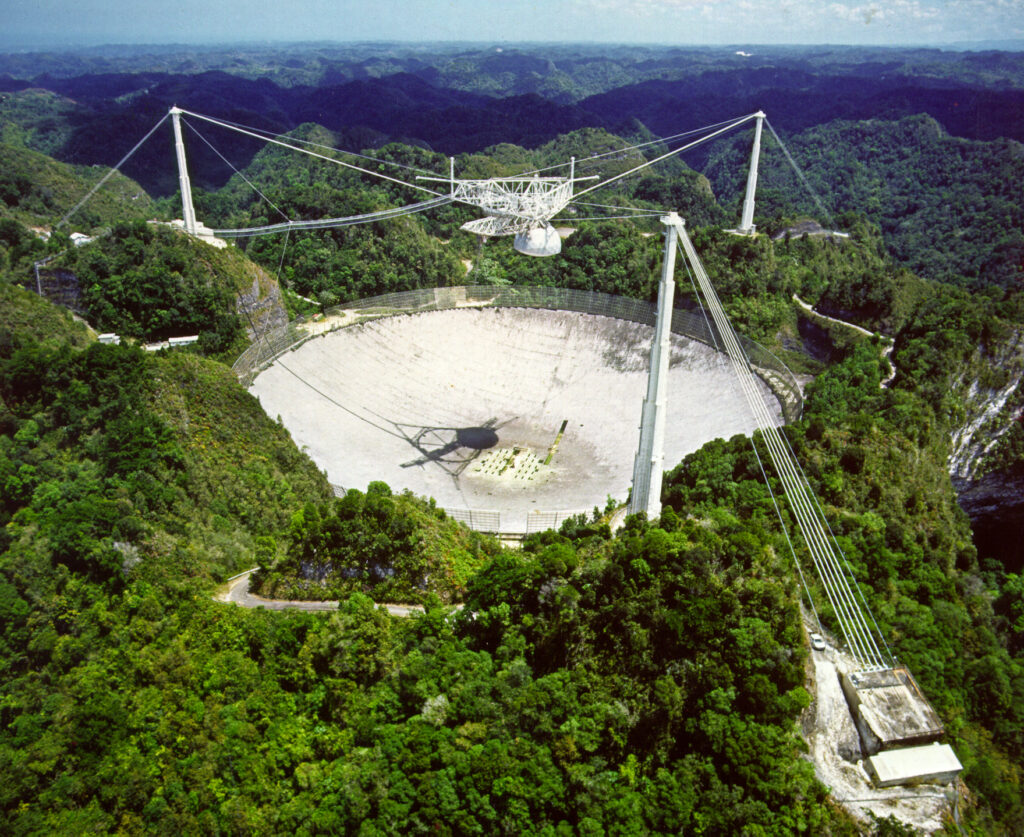 Радиотелескоп Аресибо. Приемник находился над антенной, где удерживался тросами, закрепленными на трех башнях вокруг нее.