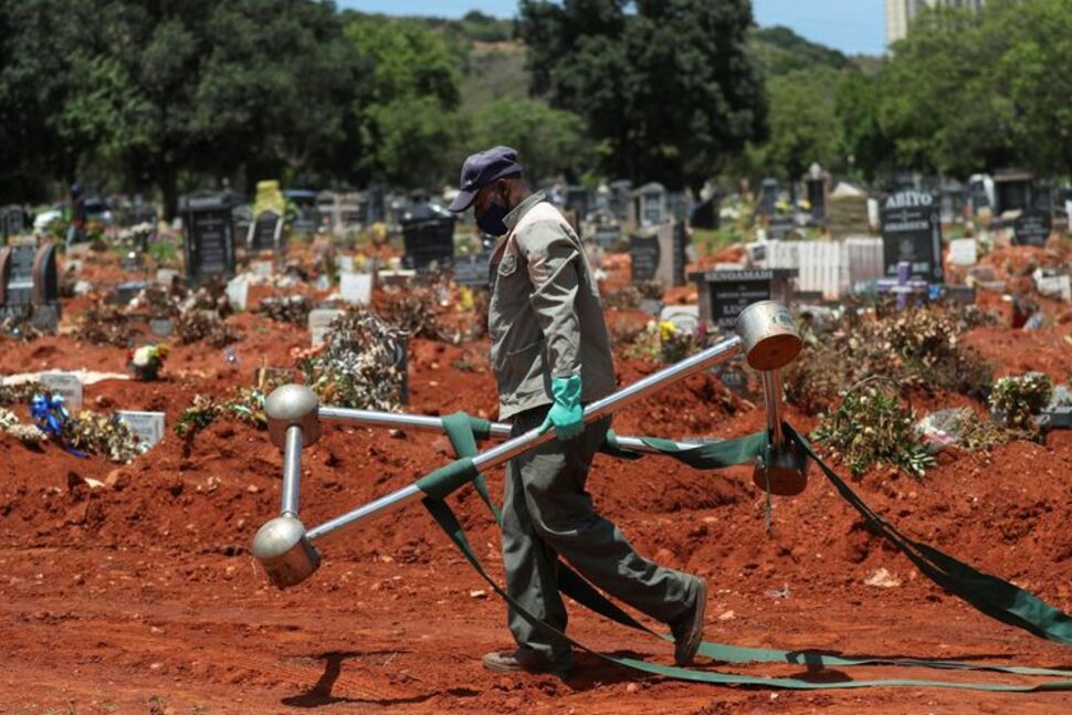 Йоханнесбург, провинция Гаутенг, ЮАР. Рабочий, обеспечивающий похороны коронавирусных больных, несет специальное приспособление для относительно бесконтактного опускания гроба в могилу / ©Reuters