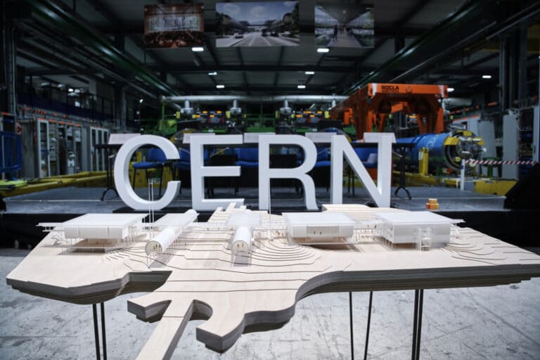 Логотип Европейской организации по ядерным исследованиям на фоне макета нового образовательного и информационно-просветительского центра CERN Science Gateway