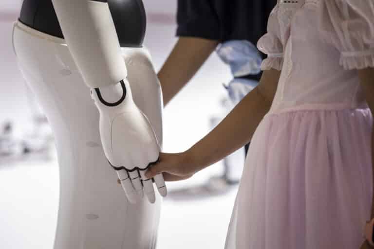 Ребенок держит за руку робота-гуманоида на Всемирной конференции по искусственному интеллекту / © Qilai Shen / Bloomberg