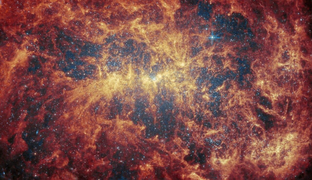 На снимке инструмента среднего инфракрасного диапазона (MIRI) запечатлен пыльный «скелет» галактики NGC 4449, который повторяет линию перемычки, но пыль кажется более плотно сконцентрированной вокруг нее / © ESA / Webb / NASA & CSA / A. Adamo (Stockholm University) and the FEAST JWST team